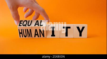 Symbole de l'égalité et de l'humanité. Main d'homme d'affaires. Cubes tournés avec des mots égalité et humanité. Beau fond orange. Affaires et égalité et Banque D'Images