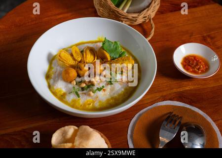 Bubur ayam, une cuisine traditionnelle indonésienne. Bouillie de riz avec poulet tranché, omelette roulée, arachide, sambal (sauce Chili) et kerupuk (craquelins), p Banque D'Images