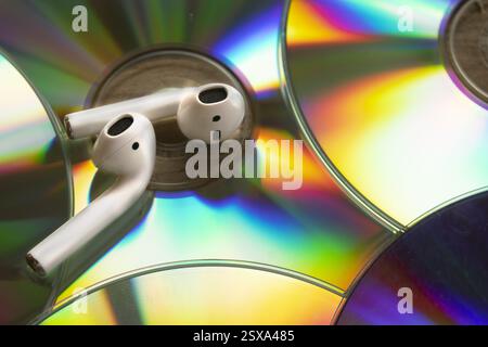 détails des reflets colorés sur les vieux disques compacts avec deux écouteurs sans fil sur le dessus Banque D'Images
