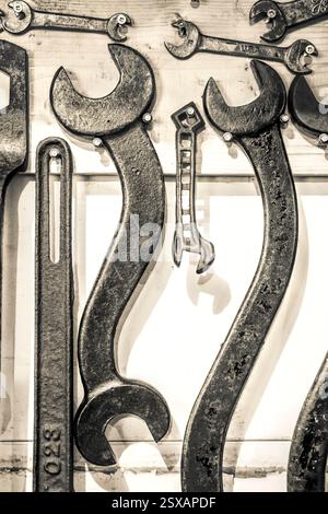 Collection de vieux outils comprenant une clé et un tournevis. La clé est accrochée au mur Banque D'Images