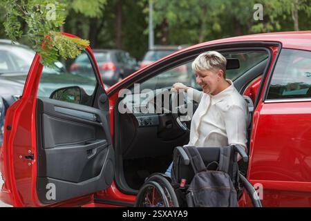 Femme handicapée qui sort de la voiture et passe du siège du conducteur au fauteuil roulant. Concept de vie autonome. Banque D'Images