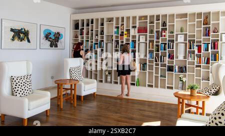 Deux personnes regardant la sélection de livres gratuits dans le hall de l'hôtel H10 Lanzarote Gardens avec sièges. Banque D'Images