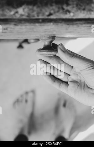 La main de la femme ouvre l'ancien tiroir de cuisine dans la cuisine à la maison, vue de dessus en bas, meubles de cuisine, photo noir et blanc Banque D'Images