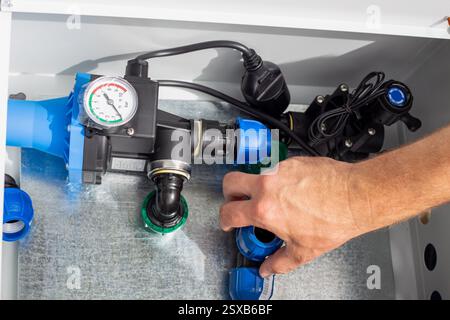 Un homme installe un système d'irrigation goutte à goutte en plaçant un tee-shirt de compression en polypropylène dans une boîte métallique. Banque D'Images
