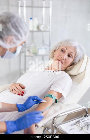 Femme médecin faisant l'injection à la vieille femme fatiguée endormie dans la clinique. Banque D'Images