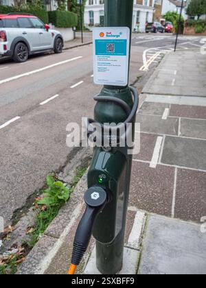 Une voiture électrique se recharge à partir d'une borne de recharge Shell dans un lampadaire de bord de route à Barnes, Londres, Royaume-Uni. Banque D'Images