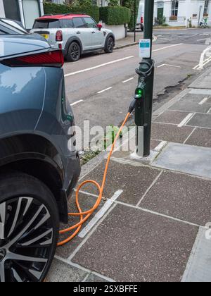 Une voiture électrique se recharge à partir d'une borne de recharge Shell dans un lampadaire de bord de route à Barnes, Londres, Royaume-Uni. Banque D'Images