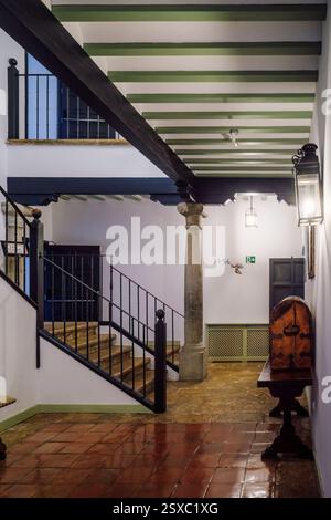 Couloir classique avec plancher de tuiles rouges antiques, plafond poutres en bois et escalier avec balustrade en fer antique à Parador de Turismo dans la ville d'Almagro, Espagne. Banque D'Images