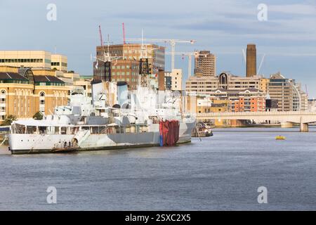 Le HMS Belfast, un navire de guerre historique, est amarré sur la Tamise à Londres, en Angleterre, près des gratte-ciel de la ville. Les travaux se poursuivent à proximité. Banque D'Images