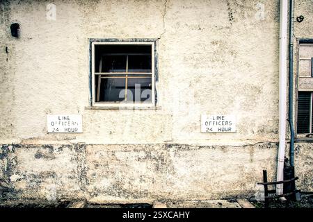 Bâtiment blanc avec une fenêtre et deux panneaux sur le mur. Un panneau indique « Line Officers 24 heures » et l'autre indique « Line Officers 24 heures » Banque D'Images