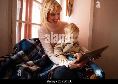 Détendez-vous, à la maison. Fils avec mère utilisant la tablette pour l'apprentissage en ligne, jouer à des jeux, regarder la vidéo sur le site Web. Banque D'Images