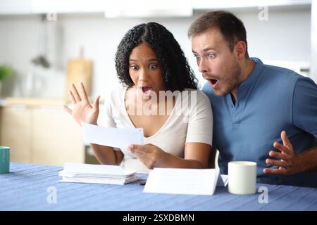 Couple étonné lisant le relevé bancaire dans la cuisine à la maison Banque D'Images