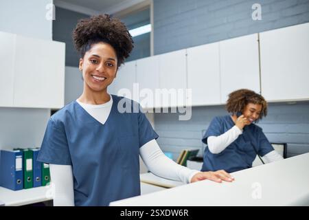 Professionnel de santé féminin souriant en uniforme travaillant à un bureau d'accueil médical Banque D'Images