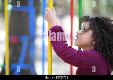 Fille souriante saisissant des bars colorés de terrain de jeu, cherchant excit Banque D'Images