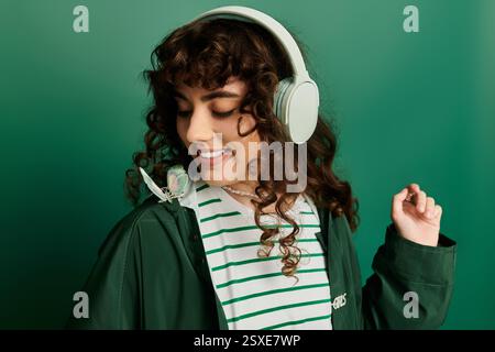 L'émotion brille comme une jeune femme à la mode porte des écouteurs, souriant avec un papillon à proximité. Banque D'Images