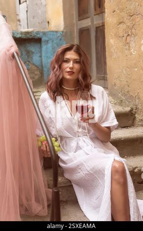 jeune femme mangeant du raisin et buvant du vin rouge Banque D'Images