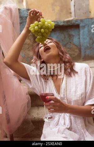 jeune femme mangeant du raisin et buvant du vin rouge Banque D'Images