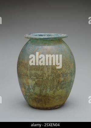 Urne cinéraire en verre bleu-vert translucide (olla) datant de la période romaine, du milieu du 1er au 2ème siècle de notre ère. Cette urne a été utilisée pour stocker les cendres, avec des intempéries irisées distinctives à l'intérieur et à l'extérieur. Banque D'Images