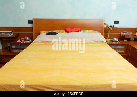 Lit non fait avec un masque de sommeil et un oreiller en forme de coeur suggère une nuit de sommeil reposante Banque D'Images