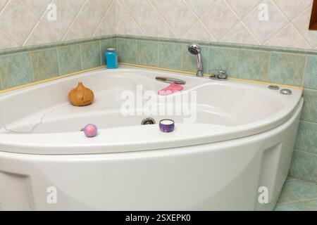 Baignoire d'angle blanche préparée pour un bain relaxant avec des produits d'aromathérapie et de bien-être Banque D'Images