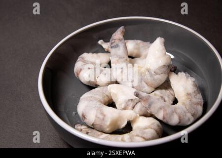 Crevettes tigrées crues congelées crevettes dans un bol gris sur une table de cuisine grise Banque D'Images