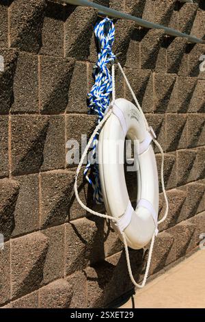 Le préservatif blanc est suspendu à une corde bleue et blanche. La corde est attachée à un mur. Le sauveteur est suspendu à la corde, et ce n'est pas le cas Banque D'Images