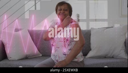 Image de l'électrocardiographe au-dessus d'une femme biraciale âgée avec patch sur le bras Banque D'Images