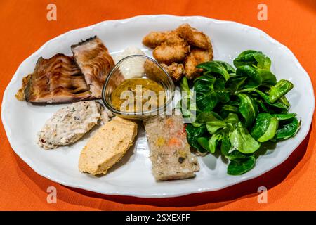 Une assiette de hors-d'œuvre avec du carpion fumé, des morceaux de carpe frits, une sauce à la moutarde, de la laitue de moutons et divers pâtés de poisson est servie lors de la dégustation de carpe à Forchheim. Apothekenstraße, Forchheim, Bavière, Allemagne. Banque D'Images
