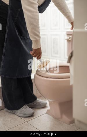 Une femme nettoyant les toilettes et la salle de bain, parfait pour le contenu sur le nettoyage, l'hygiène, l'entretien ménager et l'entretien de la maison. Banque D'Images