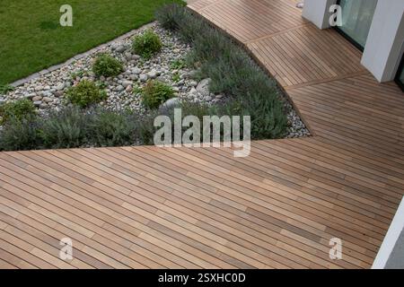 Patio extérieur conçu avec terrasse en bois et jardin paysager. Terrasse en bois entoure un jardin bien entretenu avec des pierres et divers Banque D'Images