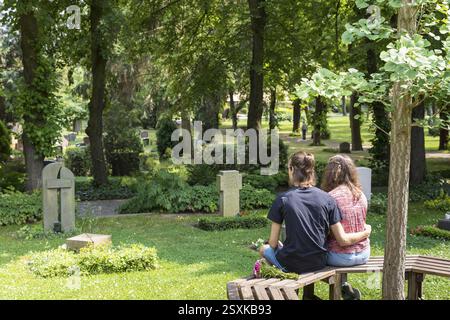 Jeune couple assis sur un banc entre des tombes d'urne, cimetière de Riesa, Saxe, Allemagne, Europe Banque D'Images