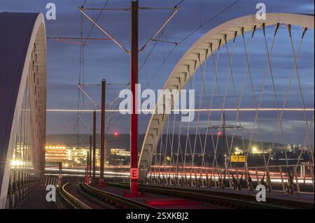 Pont ferroviaire léger moderne en carbone de Stuttgarter Strassenbahnen AG sur l'autoroute dans la soirée. Traces de lumière provenant de la circulation routière et vice-versa Banque D'Images