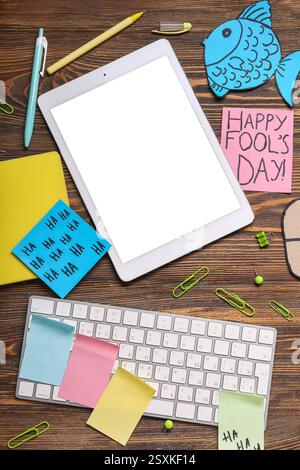 Tablette, clavier d'ordinateur, souris de carton et notes adhésives. Farce du jour des fous d'avril Banque D'Images