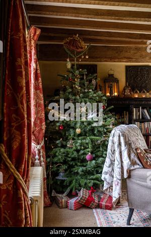 Présente sous l'arbre de Noël avec des rideaux Colelax et Fowler dans la ferme rénovée East Sussex Tudor datant de 1540, Angleterre, Royaume-Uni. Banque D'Images