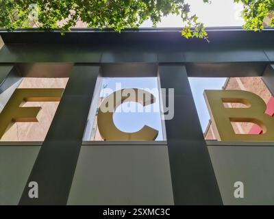 Barcelone, 18. Juillet 2024 : de grandes lettres jaunes du logo du FC Barcelona sont visibles d'en bas, encadrées par des parties du bâtiment et des branches d'arbres Banque D'Images