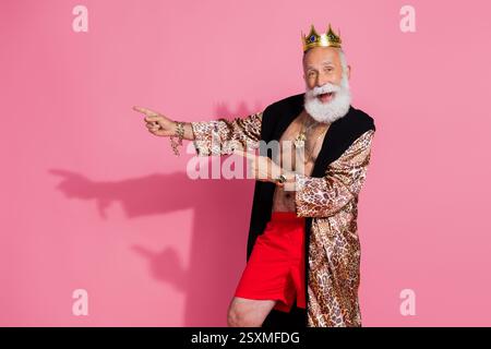 Portrait d'acteur charismatique porter manteau léopard couronne doigts directs espace vide isolé sur fond de couleur rose Banque D'Images