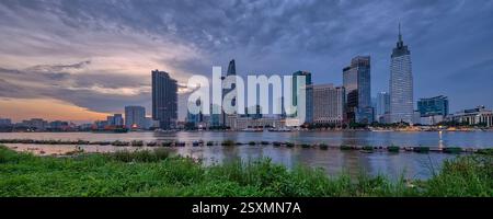 Vue panoramique de la ligne d'horizon illuminée de Ho Chi Minh ville, Thành phố Hồ Chí Minh, Saigon, Sài Gòn, reflétée dans la rivière Saigon, Sông Sài Gòn. Banque D'Images