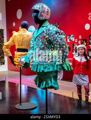 Londres, Royaume-Uni. 25 février 2025. Un membre du personnel avec «Blazer with Shorts» (tissu à fines rayures vertes avec paillettes argentées, porté à l'Alternative Miss World 1986, 1984-5, «Crash Helmet with paillettes», 1984, et «Glasses with Eyes», 1984, dans la salle 2 - Club : Would You Let You Yourself In?, lors d'une avant-première de «Leigh Bowery!», une nouvelle exposition à la Tate Modern dédiée à l'artiste défunt, consacrée à l'artiste défunt, avec de nombreux «Looks» des années 1980 et 90. L'exposition se déroule du 27 février au 31 août 2025. Credit : Stephen Chung / Alamy Live News Banque D'Images