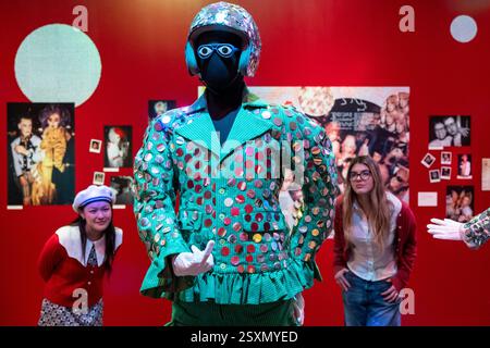 Londres, Royaume-Uni. 25 février 2025. Membres du personnel avec «Blazer with Shorts» (tissu à rayures vertes avec paillettes argentées, porté à The Alternative Miss World 1986», 1984-5, «Crash Helmet with paillettes», 1984, et «Glasses with Eyes», 1984, dans la salle 2 - Club : Would You Let You Yourself In?, lors d’une avant-première de «Leigh Bowery!», une nouvelle exposition à la Tate Modern dédiée à l’artiste défunte, avec de nombreux «Looks» des années 1980 et des années 90. L'exposition se déroule du 27 février au 31 août 2025. Credit : Stephen Chung / Alamy Live News Banque D'Images