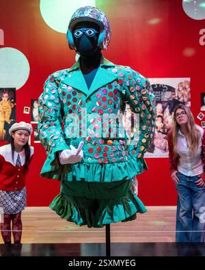 Londres, Royaume-Uni. 25 février 2025. Membres du personnel avec «Blazer with Shorts» (tissu à rayures vertes avec paillettes argentées, porté à The Alternative Miss World 1986», 1984-5, «Crash Helmet with paillettes», 1984, et «Glasses with Eyes», 1984, dans la salle 2 - Club : Would You Let You Yourself In?, lors d’une avant-première de «Leigh Bowery!», une nouvelle exposition à la Tate Modern dédiée à l’artiste défunte, avec de nombreux «Looks» des années 1980 et des années 90. L'exposition se déroule du 27 février au 31 août 2025. Credit : Stephen Chung / Alamy Live News Banque D'Images