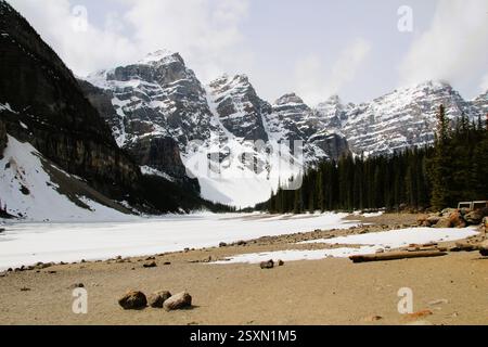 La photo capture un paysage alpin à couper le souffle, mettant en valeur un lac serein partiellement gelé, entouré de montagnes imposantes Banque D'Images