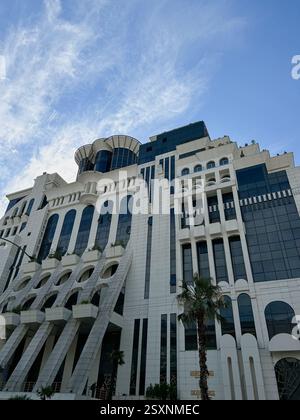 L'image capture un immeuble de grande hauteur avec un style architectural distinctif, avec des panneaux extérieurs blancs, des fenêtres en verre foncé et des géométriques Banque D'Images