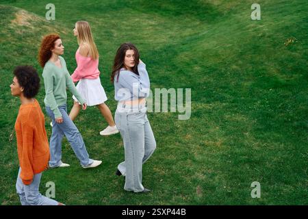 Un groupe d'amis à la mode se promène en toute confiance dans un parc verdoyant au printemps. Banque D'Images