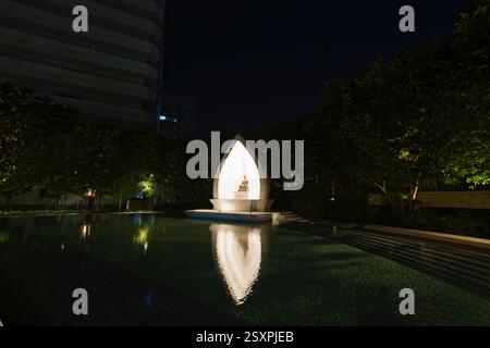 Bouddha assis illuminé avec réflexion de l'eau Banque D'Images