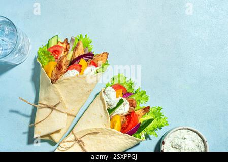 Enveloppement de gyros de poulet grec avec légumes et sauce tzatziki sur fond bleu, vue de dessus, espace de copie. Nourriture grecque saine. Doner kebab en pita maison Banque D'Images