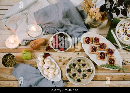Délicieux assortiment de desserts et de fruits affichés sur une table en bois avec une ambiance chaleureuse aux chandelles Banque D'Images
