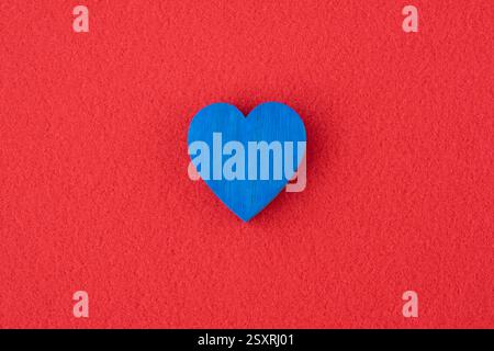 Coeur en bois bleu sur le fond de tissu rouge avec espace pour le texte. Concept de carte. Banque D'Images