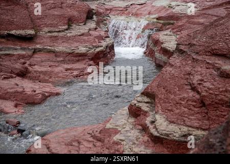 Petite cascade en cascade au-dessus de formations rocheuses rouges colorées dans le canyon de roches rouges Banque D'Images