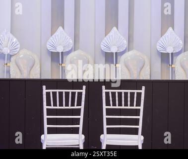 Une paire de chaises blanches sous un podium avec des sièges pour les moines bouddhistes prêts pour un rituel de mariage Banque D'Images