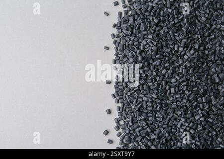 Pile de granulés de plastique noir sur fond gris, vue de dessus. Espace pour le texte Banque D'Images